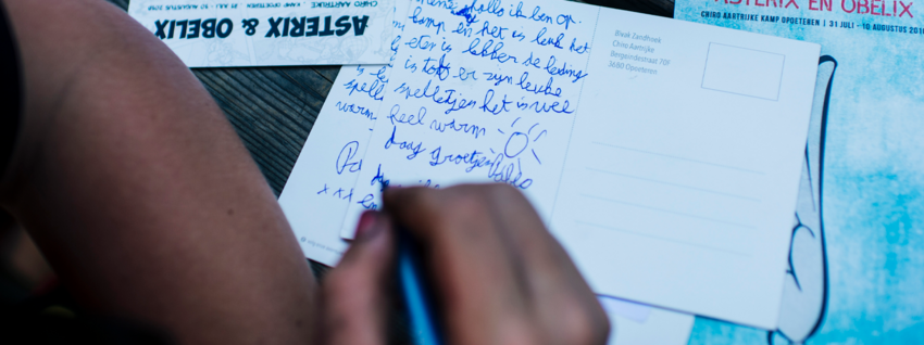Kind schrijft kaartje naar huis op kamp